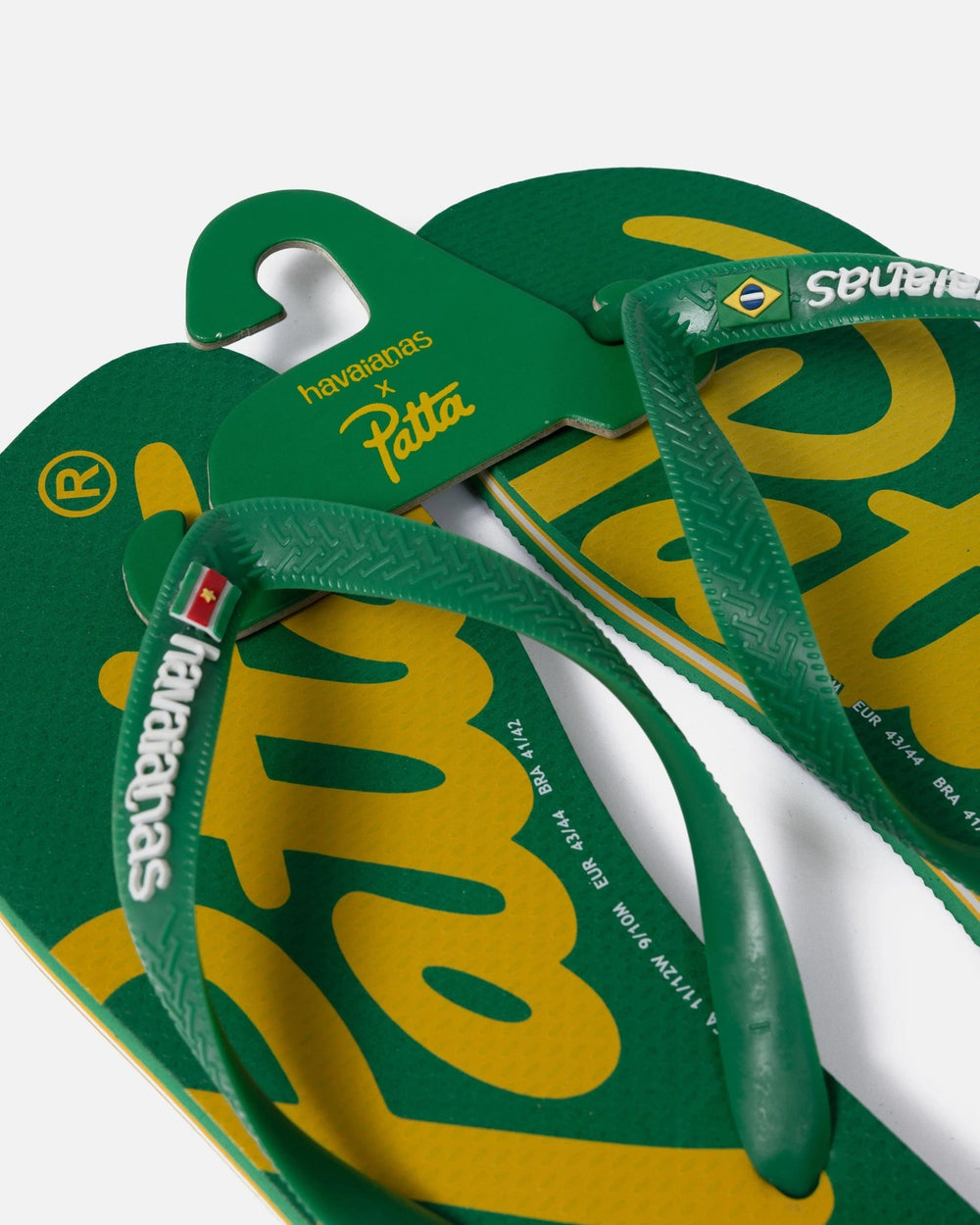 Detail of green Patta x Havaianas flip-flops featuring yellow logo footbeds and branded rubber straps.